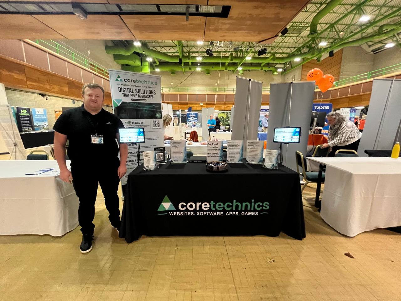 CoreTechnics stand with an exhibitor near the branded display and company table